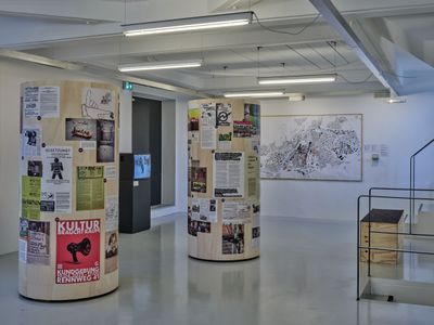 Blick in die Ausstellung im aut mit Litfaßsäulen "Kulturräume" und "Öffentliche Räume" sowie Schwarzplan von Innsbruck mit Verbots- und Schutzzonen.